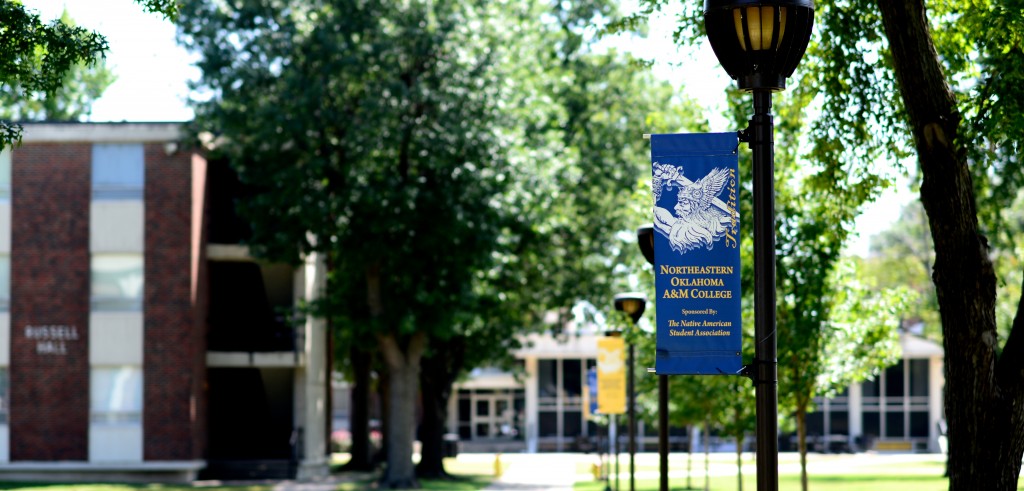 NEO campus with focus on a light pole banner, with trees in the background