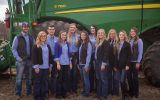Young farmers and ranchers stand together in front of a tractor