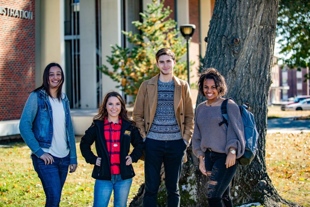 Four students stand together on the NEO campus