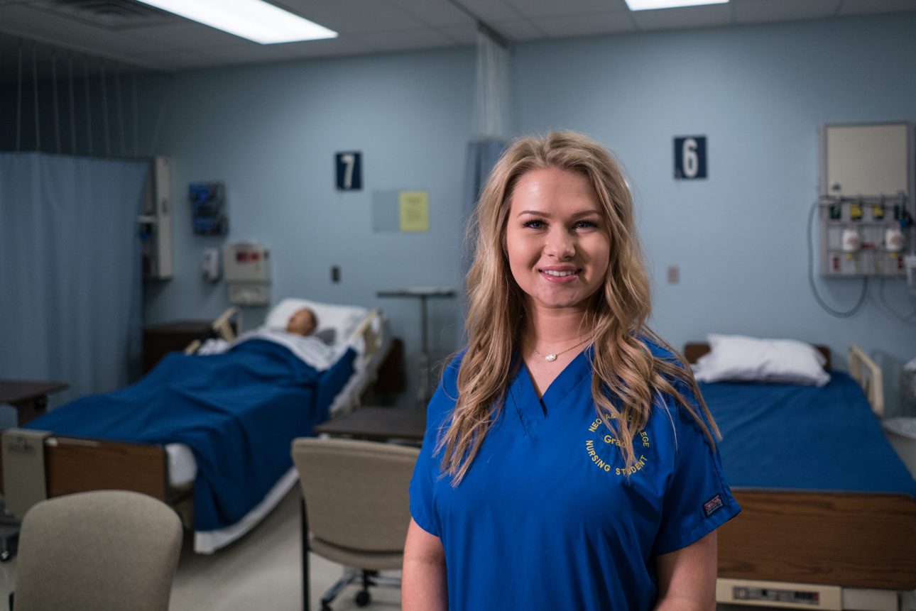 A nursing student stands in front of hospital beds