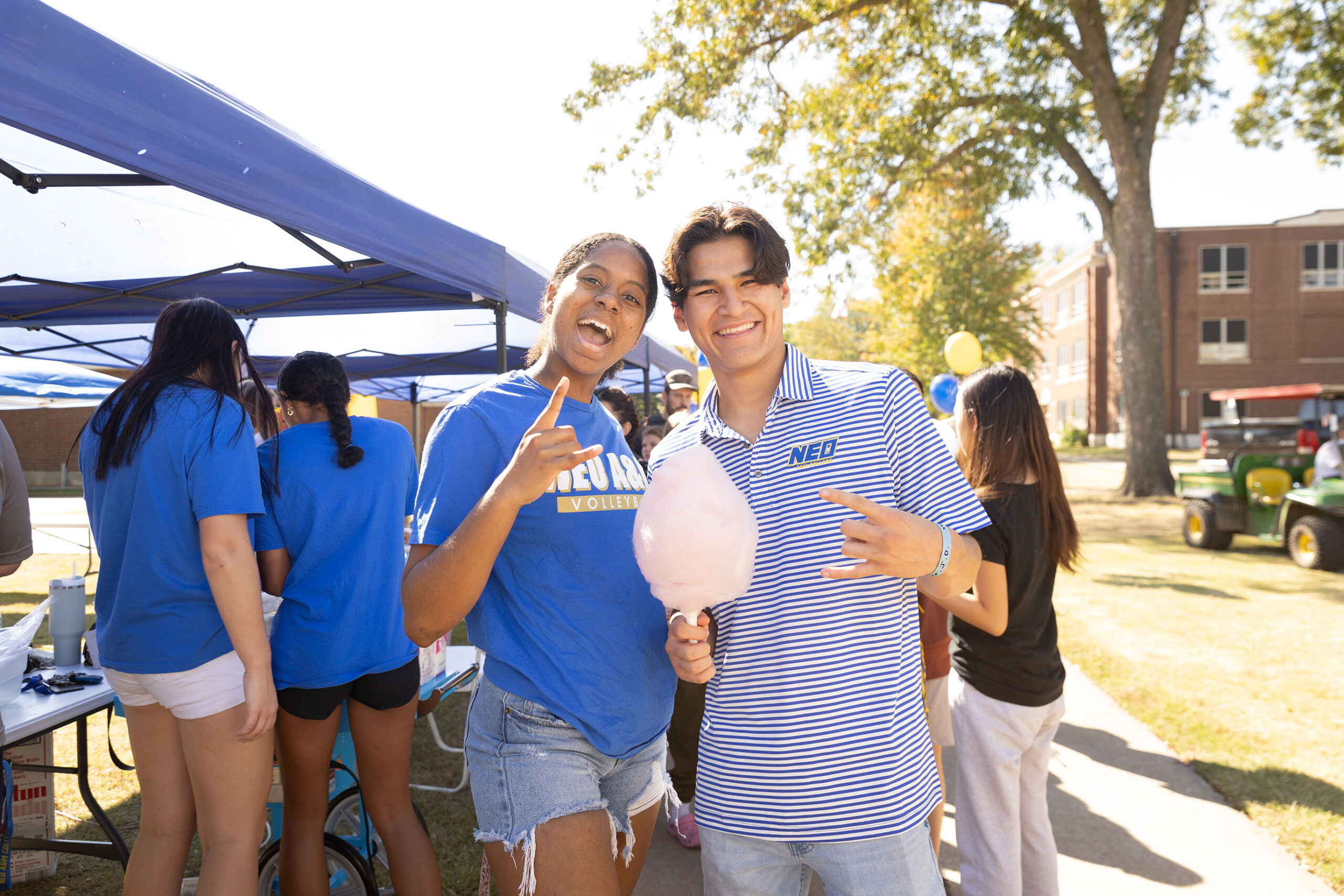 Two students smiling with cotton candy at an outdoor event