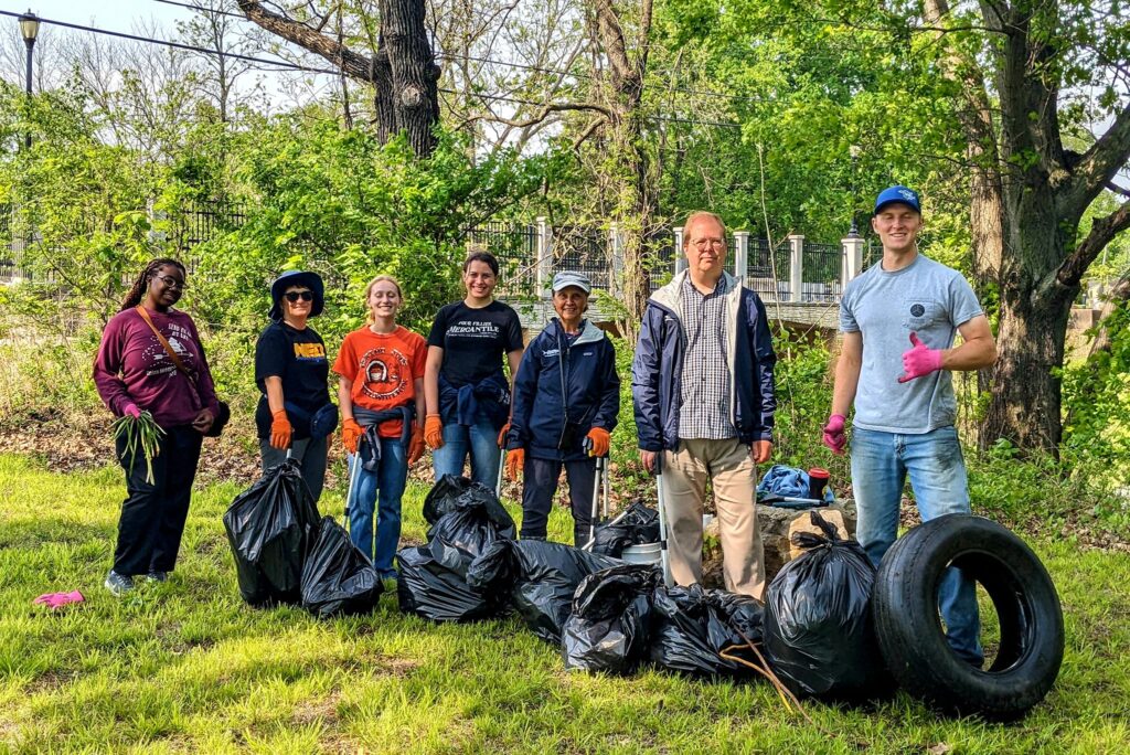 Outdoors, a volunteer group poses with collected garbage